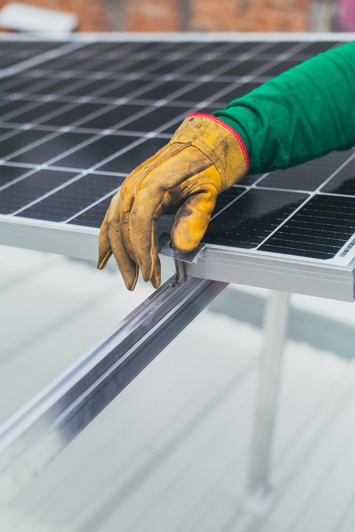Close-up of a workers hand in protective glove installing a solar panel.