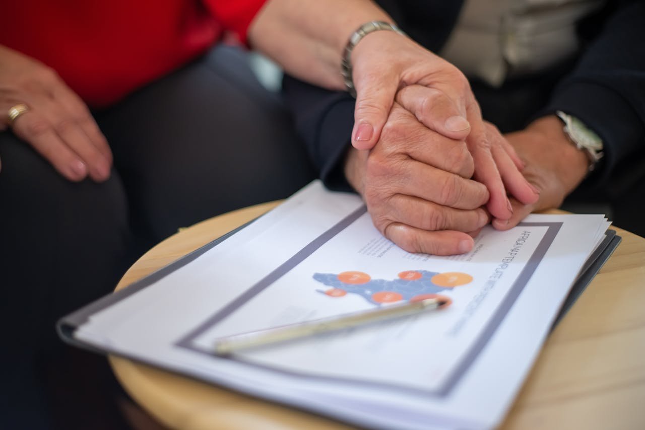 Offerings Two adults holding hands over business documents, symbolizing support and partnership.